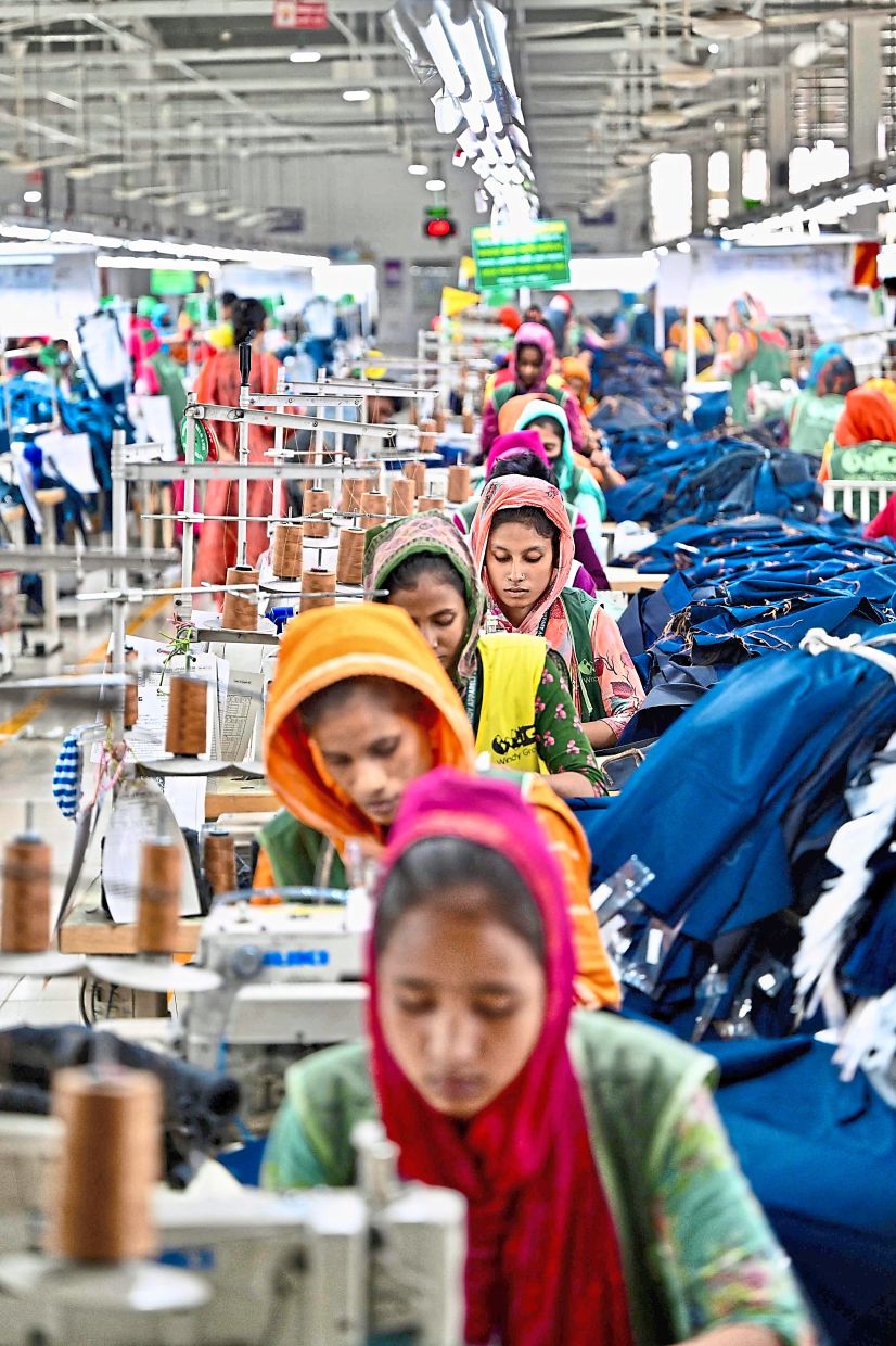 Orderly fashion: Garment workers tailoring clothes at their sewing stations in a factory in Tongi, on the outskirts of Dhaka. — AFP