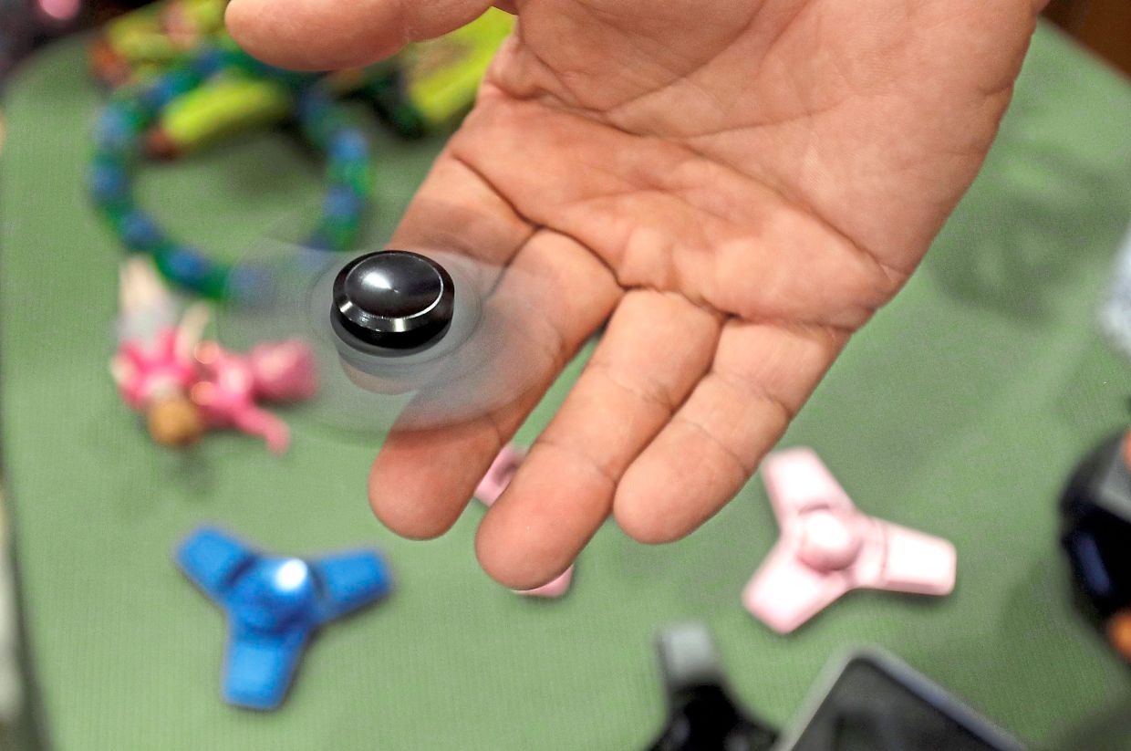 Funky Monkey Toys store owner Tom Jones plays with a fidget spinner. — CARLOS OSORIO/AP
