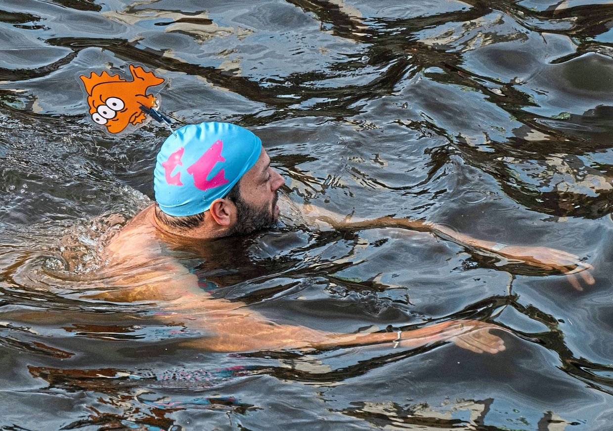 A swimmer bathes in the Spree canal during a demonstration to mark the 100th anniversary of a ban on swimming in the Spree river, Berlin. 