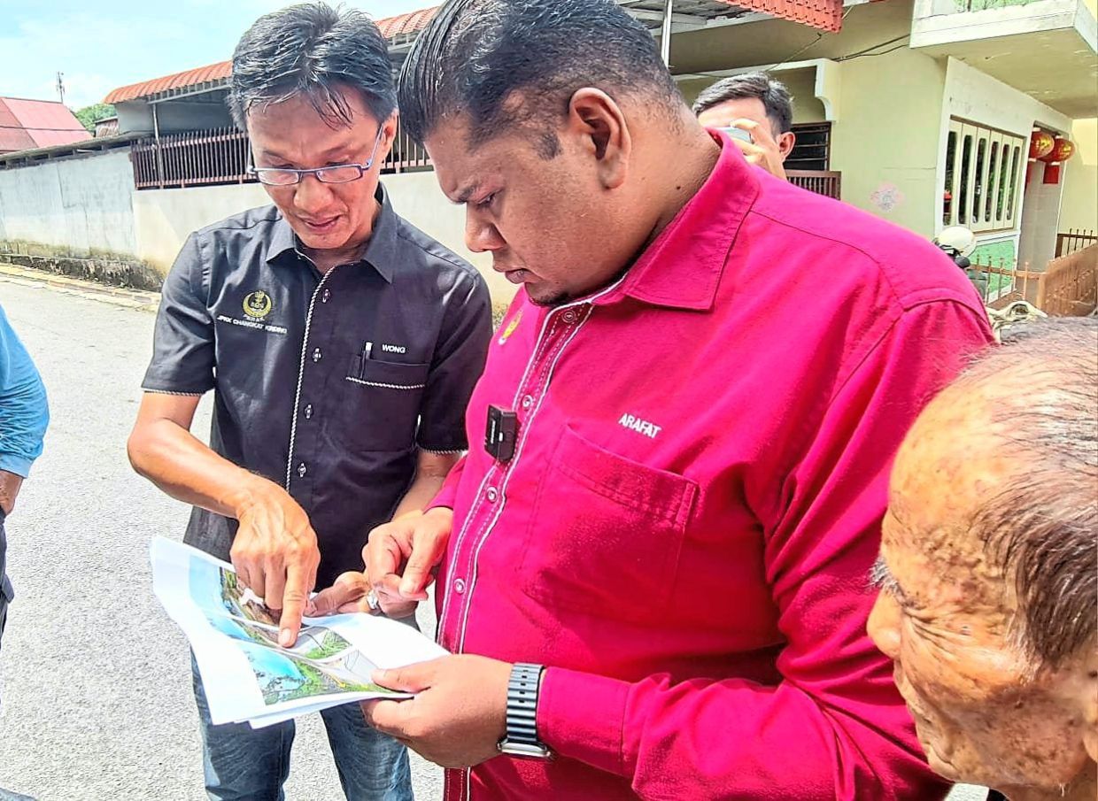 Wong (left) explaining to Mohamad Arafat the need for speed breakers at Kampung Baru Changkat Kinding.