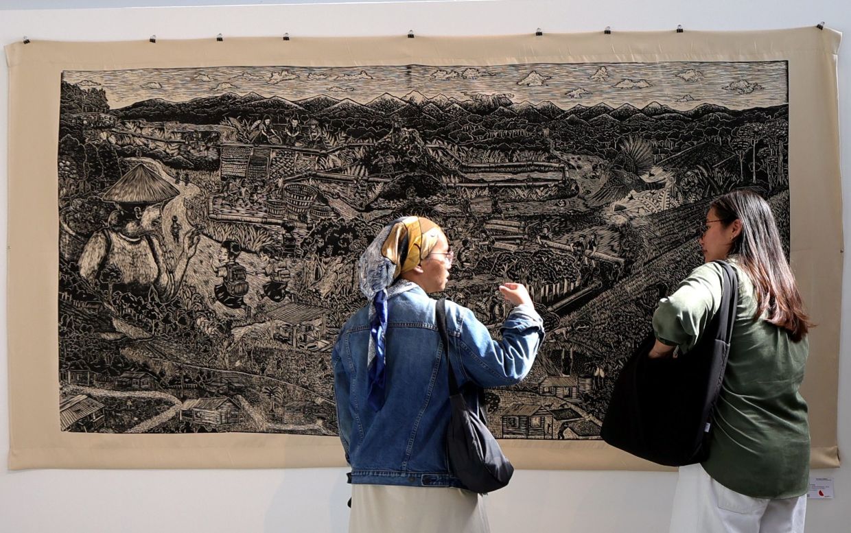 Visitors view Pangrok Sulap’s 'Cahaya Adalah Kehidupan' (2022), a woodcut on blackout fabric, at the Sabahan collective’s 'The Sound Of Salience' exhibition at Tali Art Gallery, Petaling Jaya. Photo: The Star/Chan Tak Kong