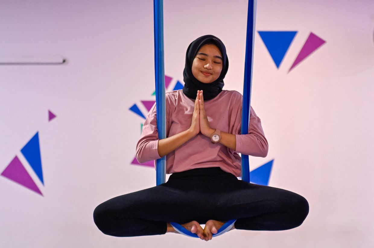 A woman practices aerial yoga during a session at a gym for women only in Banda Aceh on Saturday, July 19, 2025. (Photo by CHAIDEER MAHYUDDIN / AFP)
