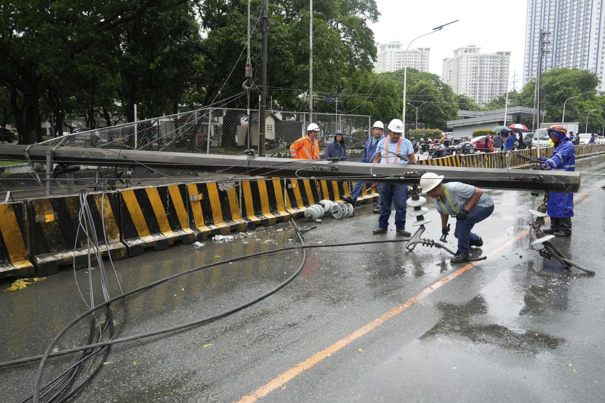Workers dismantle a toppled electrical post in Quezon city, Philippines due to torrential winds and rain as Tropical Storm Wipha, locally called Crising, exits the northern portion of country on Saturday, July 19, 2025. - Photo: AP