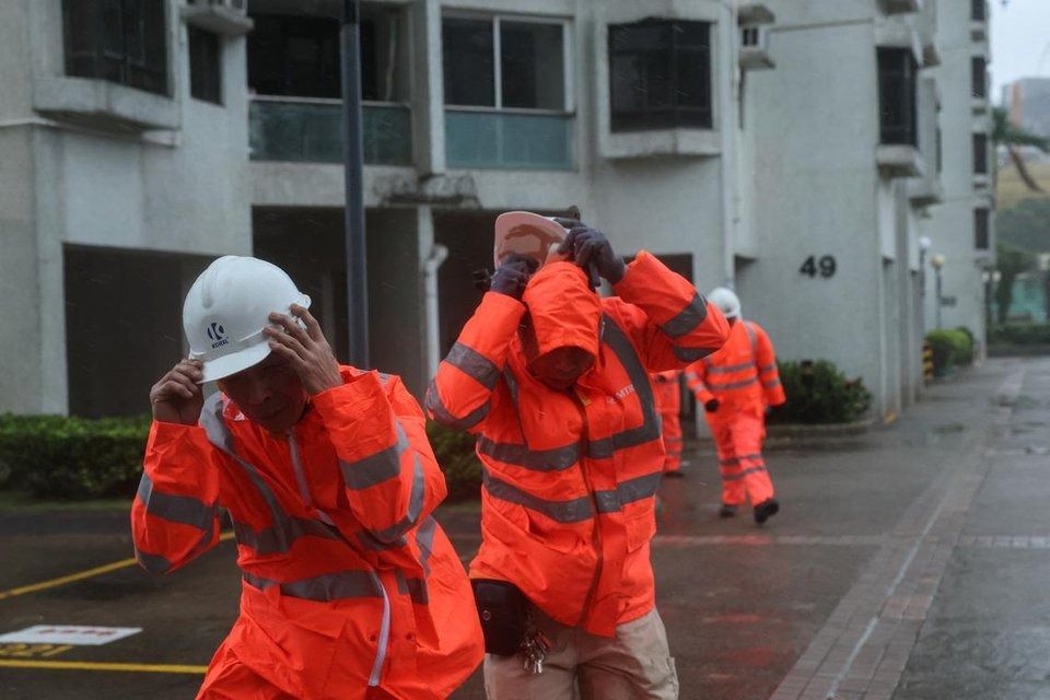 Workers braving strong winds as Typhoon Wipha approaches in Hong Kong, on July 20. - Photo: Reuters