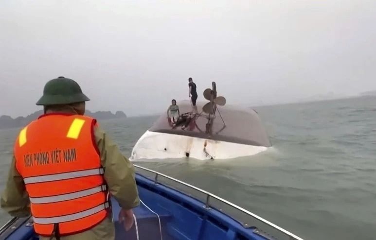This image from a video provided by QDND shows people on a capsized tourist boat being rescued in Halong Bay, Vietnam on Saturday (July 19, 2025). - Photo: QDND via AP 
