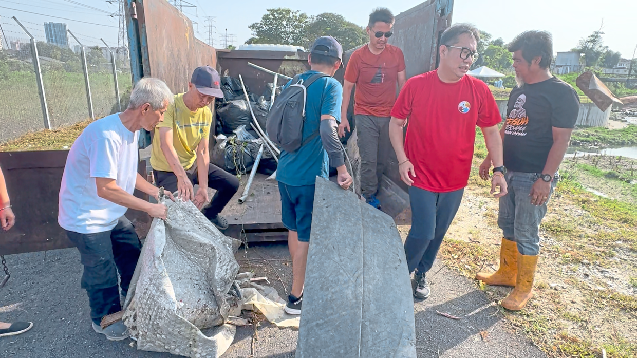 Volunteers hauling the collected rubbish from the river into a roll-on roll-off bin provided by MBPJ.