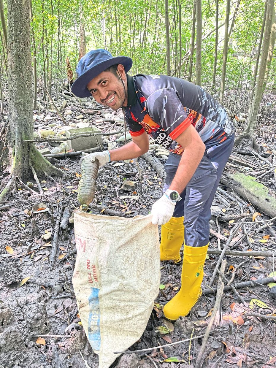 A volunteer helping to extract small items like plastic bottles from hard-to-reach areas at the mangroves along Sungai Klang. 
