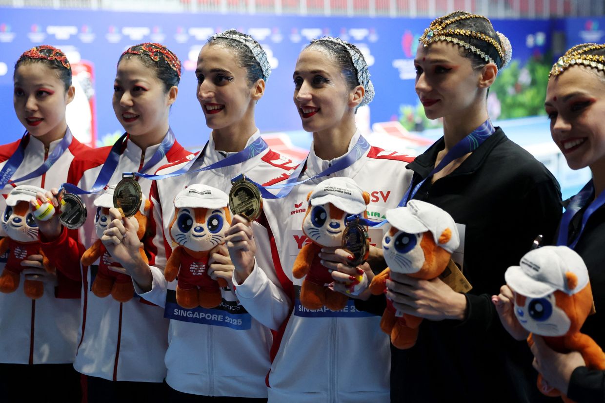 Artistic Swimming - World Aquatics Championships - Women's Duet Technical Final - World Aquatics Championships Arena, Singapore - Monday, July 21, 2025; Gold medallists Austria's Anna-Maria Alexandri and Eirini-Marina Alexandri pose during the women's duet technical final medal ceremony with silver medallists China's Yanhan Lin and Yanjun Lin and bronze medallists Neutral Athletes B's Mayya Doroshko and Tatiana Gayday. -- Photo: REUTERS/Hollie Adams