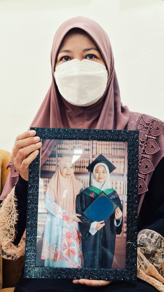 Noraidah Lamat showing a photo taken with her only child, Zara Qairina Mahathir, who passed away last week after being found unconscious beneath her dormitory block on Wednesday (July 16).