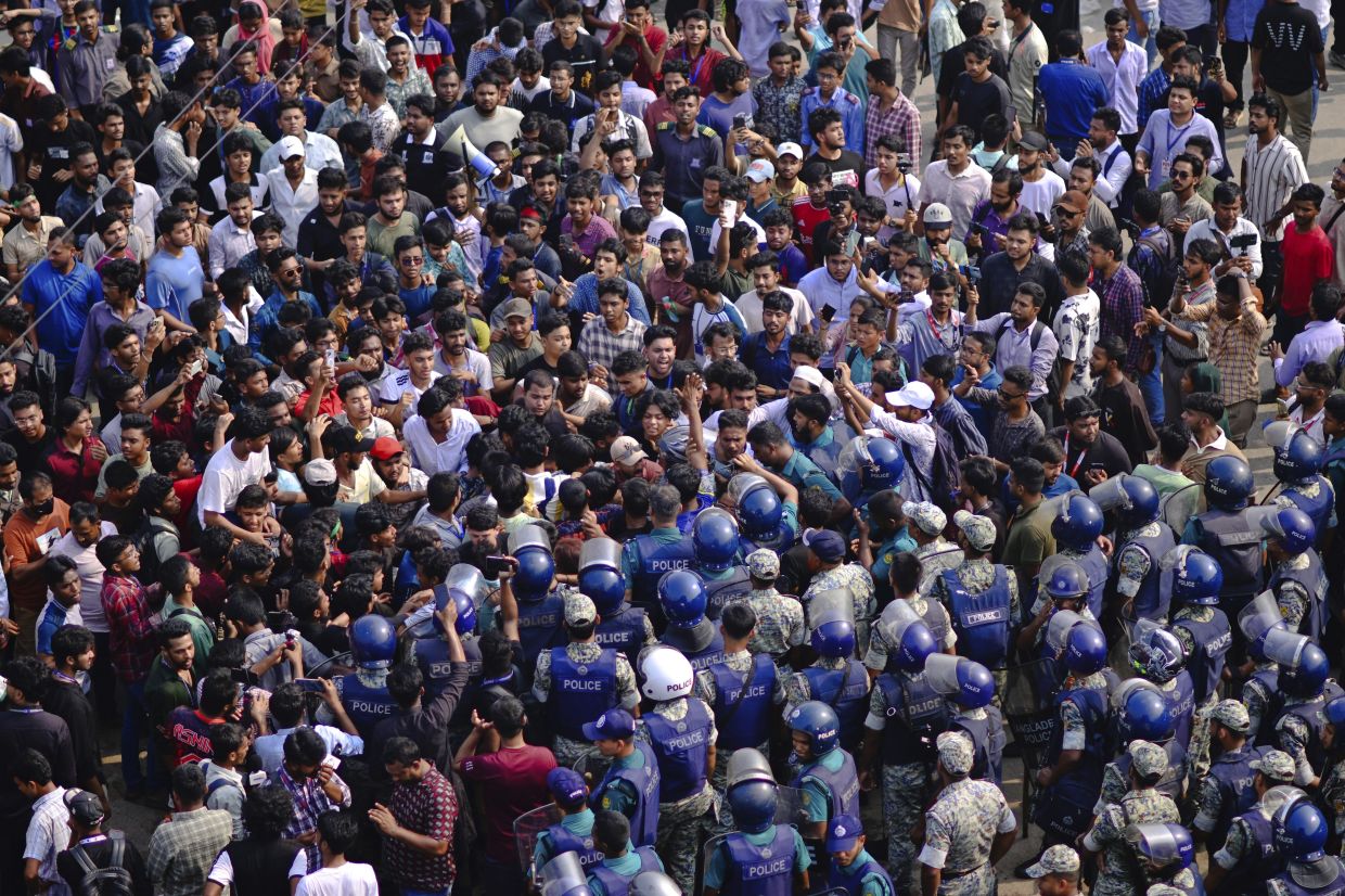Police officers stand guard as students shout slogans during a protest near the site of the crash of a Bangladesh air force training jet into a school, demanding accountability, compensation for victims' families and the halt of training flights, in Dhaka, Bangladesh, Tuesday, July 22, 2025. - Photo: AP 