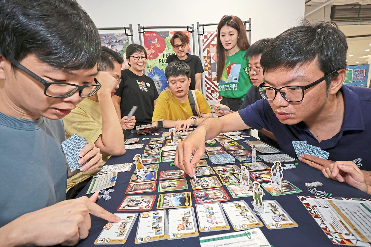 Goh (standing, left) looking on as players get engrossed with the board game ‘Kaki Lima’ featuring George Town’s famous five-foot ways.
