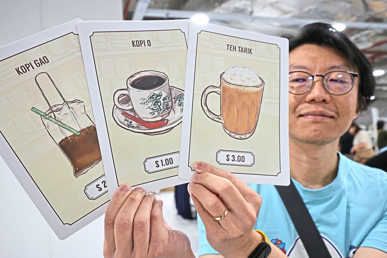 Pang showing cards for the coffeeshop-based game ‘Kopi King’ where players are required to make popular drinks, with the winner making the highest in earnings.
