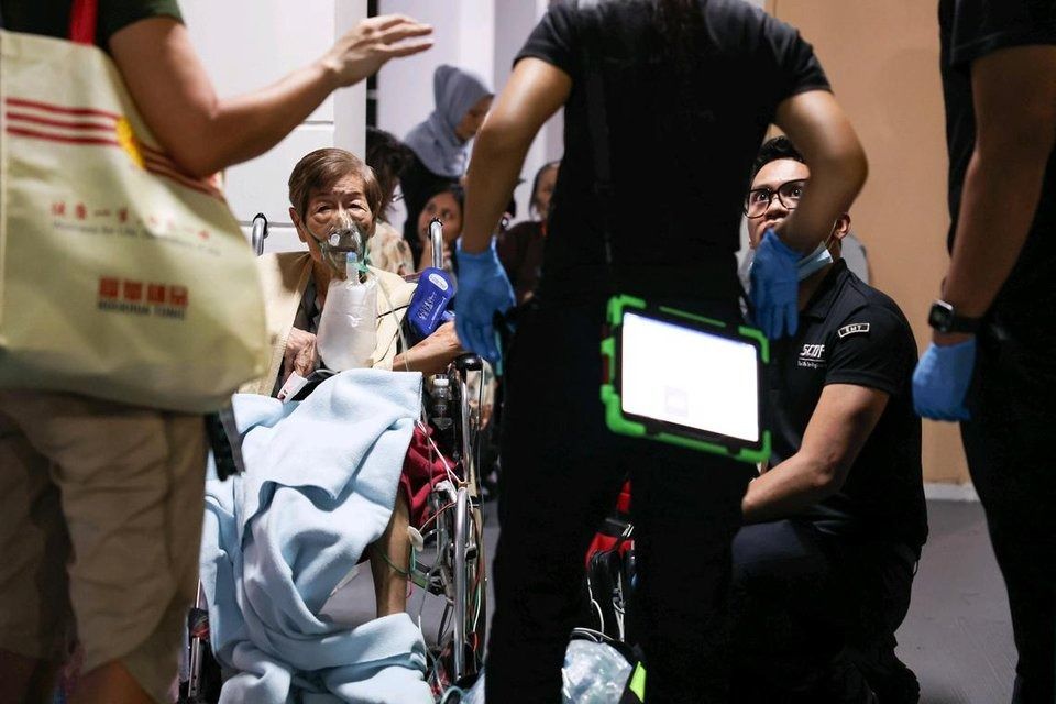 SCDF personnel assisting residents at the void deck of Block 172A, Toa Payoh Lorong 1, near the block where a unit caught fire. - ST