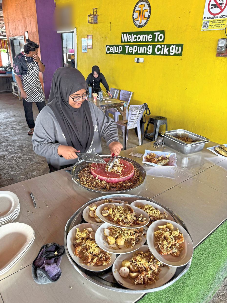 Noor Syafiqah preparing the fried seafood dishes.