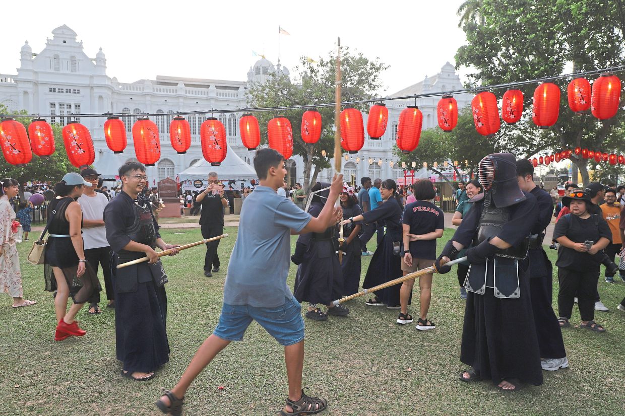 Visitors learning kendo moves from exponents.