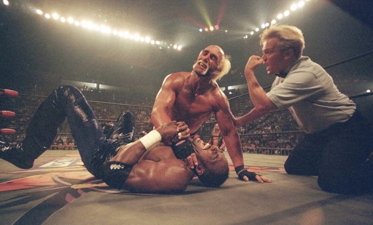 Hollywood Hulk Hogan puts a choke hold on the neck of Utah Jazz basketball star Karl Malone at a pay-per-view wrestling match July 12, 1998, in San Diego. (AP Photo/Lenny Ignelzi, File)