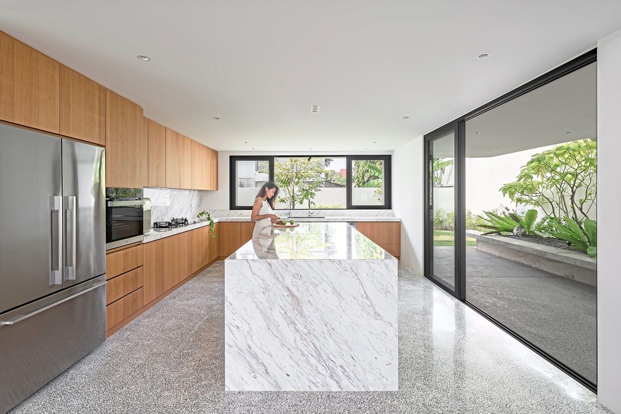 The kitchen is a warm, welcoming space with a mix of marble, timber and soft ambient lighting.