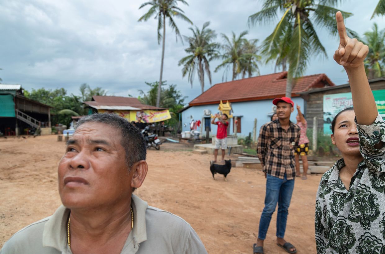 A resident of Samraong, the capital of Cambodia's Oddar Meanchey province, pointing to where she sees an aircraft being fired at by Cambodian forces on July 25, 2025. - AP