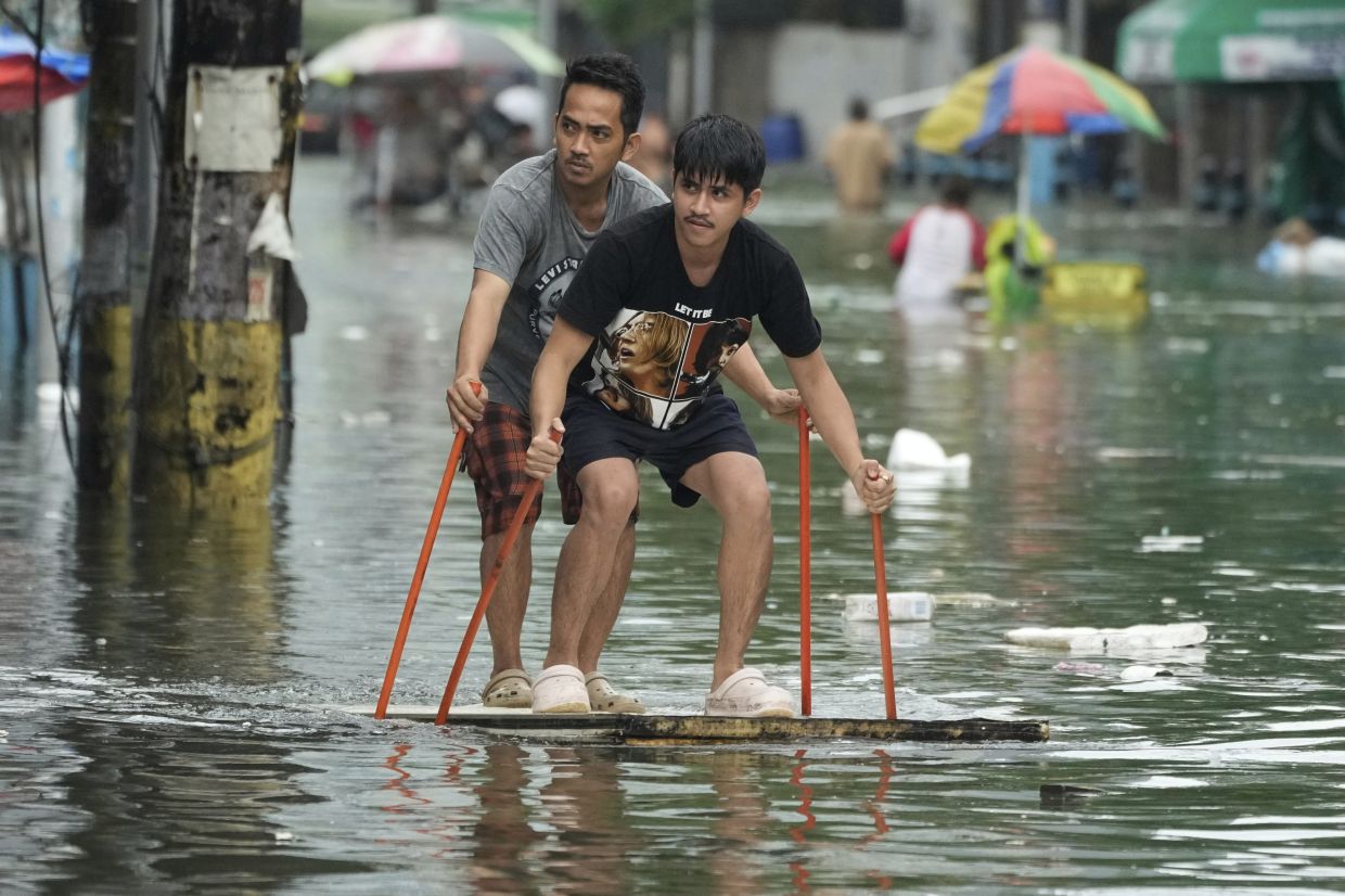 Residents use poles as they ride an improvised float along a flooded road as Typhoon Co-may intensified seasonal monsoon rains at Malabon city, Philippines on Friday, July 25, 2025. - Photo: AP