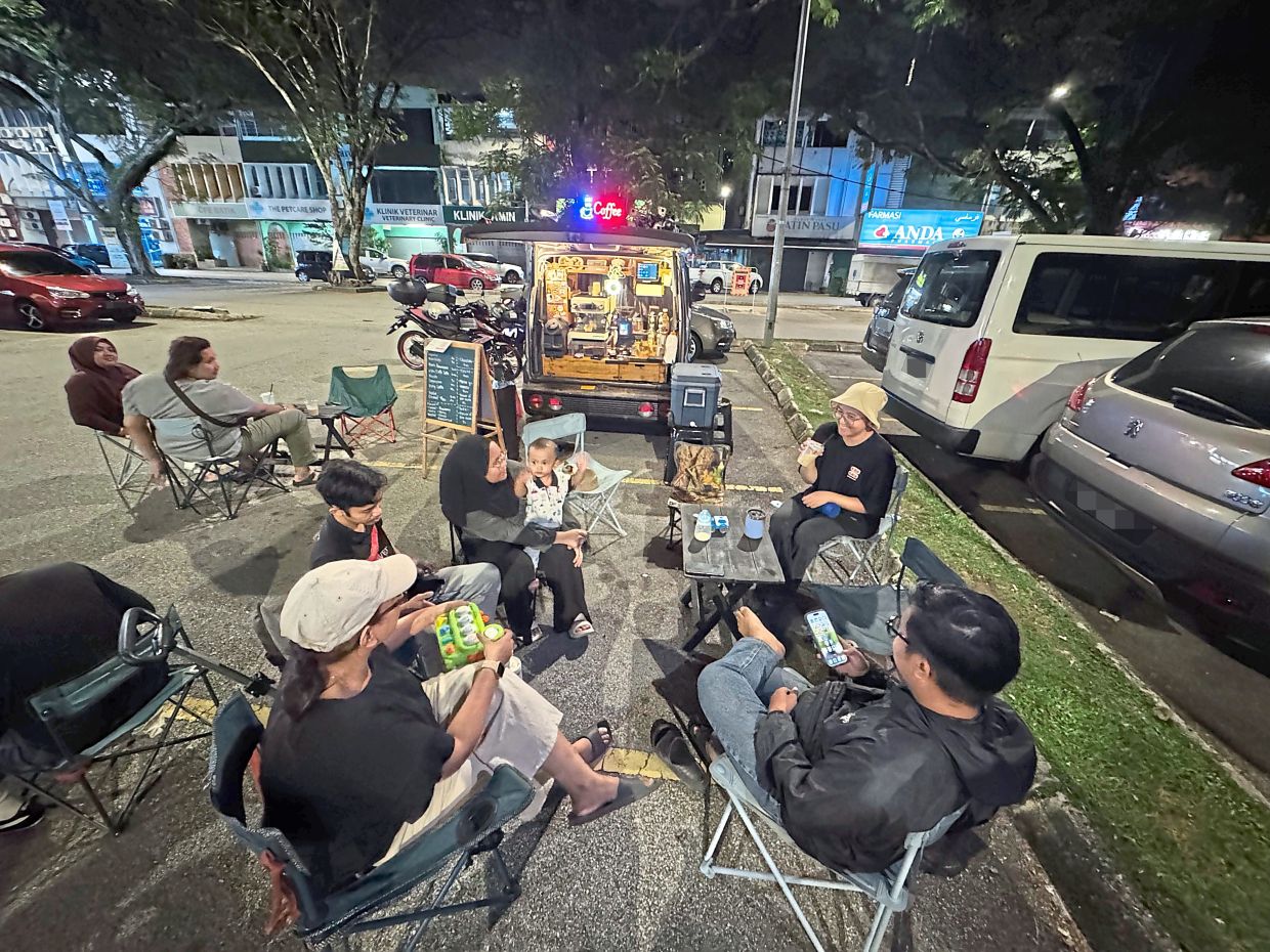 Hanim (second from right) sitting with some customers at her pop-up coffee stall.