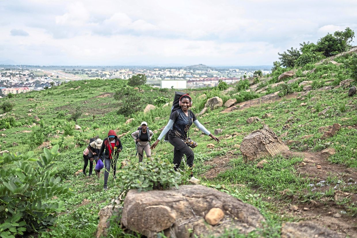 A hiker leads a group along a rocky path as they climb a hill during a group hike.