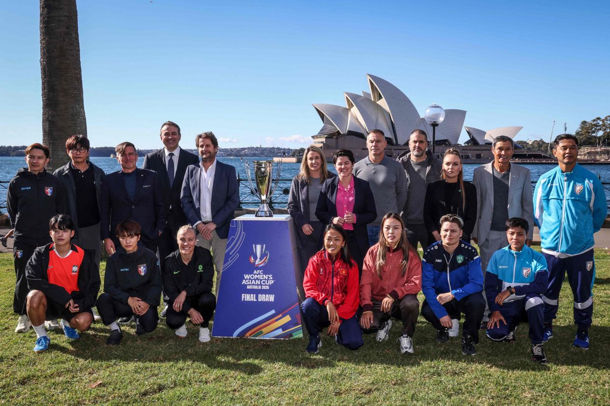 Officials, team coaches, and players from Japan, China, India, Taiwan, South Korea, Australia, Vietnam, Philippines, and Uzbekistan pose for a photograph with the 2026 AFC Women's Asian Cup trophy ahead of the official draw, opposite the Sydney Opera House in Sydney on July 28, 2025. The 2026 AFC Women's Asian Cup will be hosted by Australia, and will run from March 1 to 21, 2026. -- Photo by DAVID GRAY / AFP
