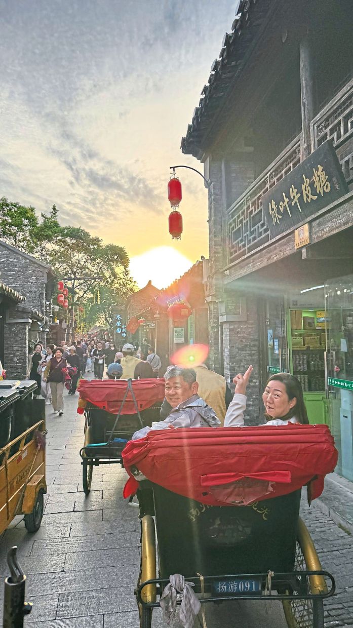 位于江苏省扬州的马来西亚游客，高兴地骑着三舍五来探索这座城市的历史遗迹。