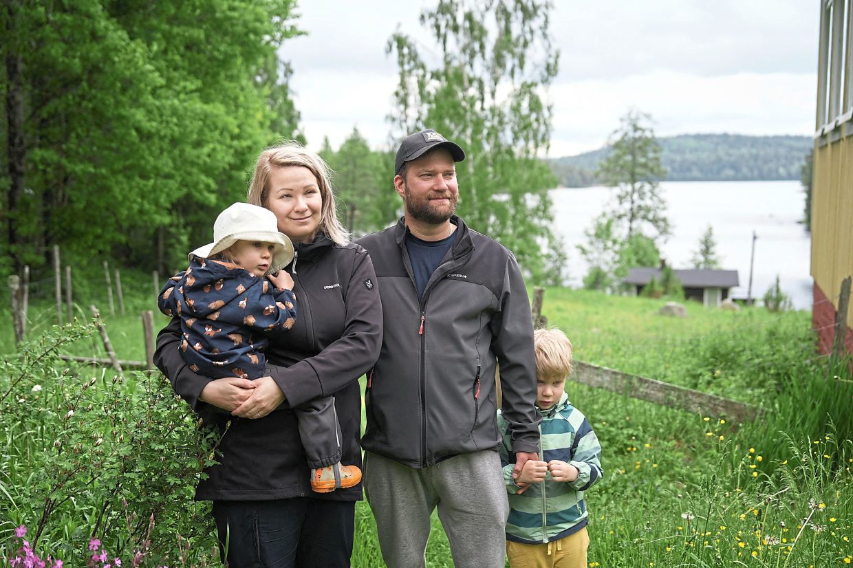 Oona holding Fia, with her husband Petri and their son Hugo posing outside their rented cottage.