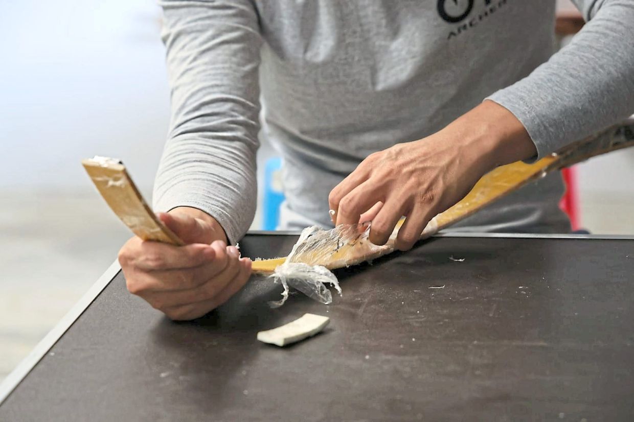 A plastic protective coat is removed before the bow blank is ground into shape on a belt sanding machine.