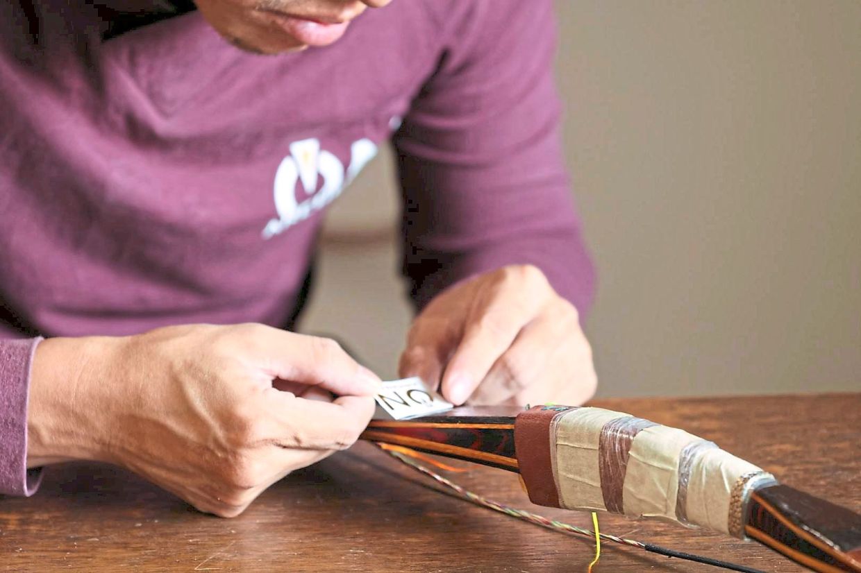 Wong applying the finishing touches on a custom-made bow.