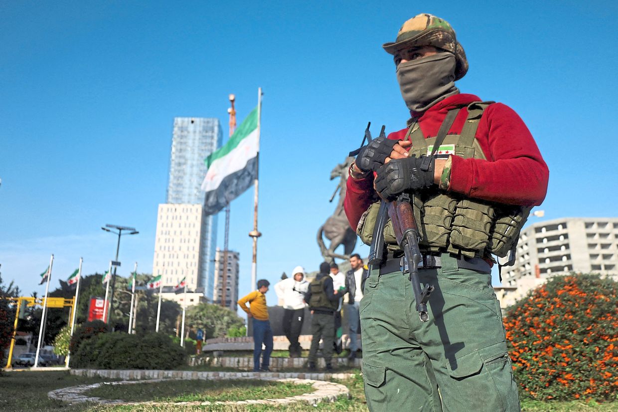 A fighter of the ruling Syrian body standing while holding a weapon, after violence in Tartous province. — Reuters
