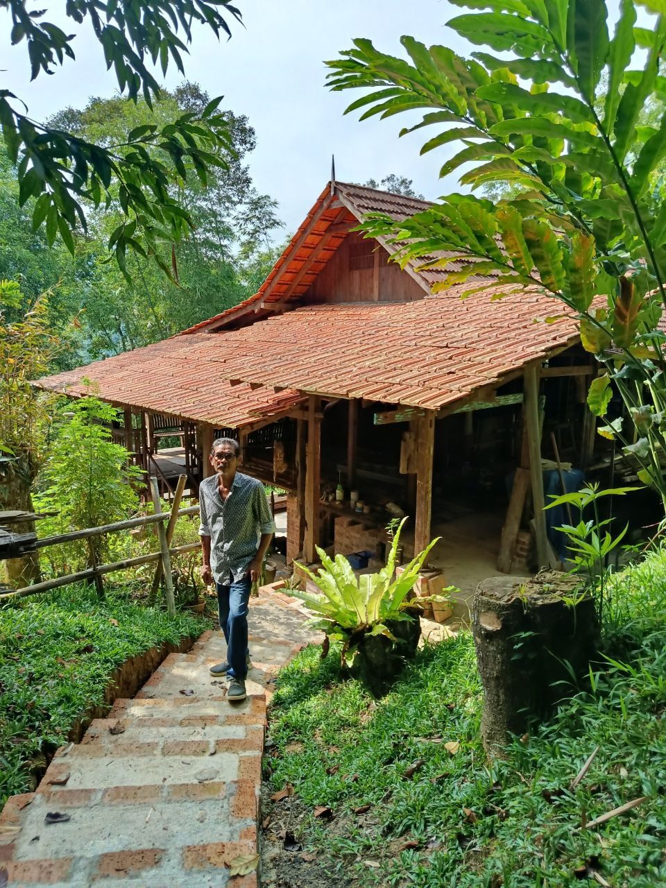 Zainal standing proud in front of his house, which he built with his own two hands.