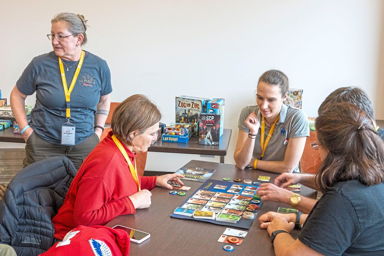 Beyer (left) stands next to Jager (third from right) at a gaming table at a meeting of members of the Mensa association for the gifted.