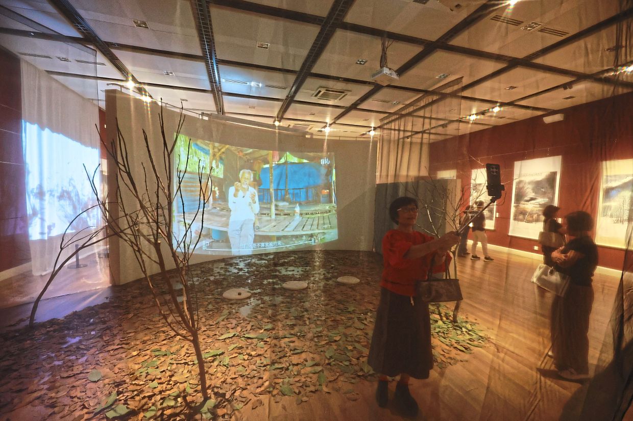 A visitor taking a selfie at an interactive section depicting the life of rubber tappers.