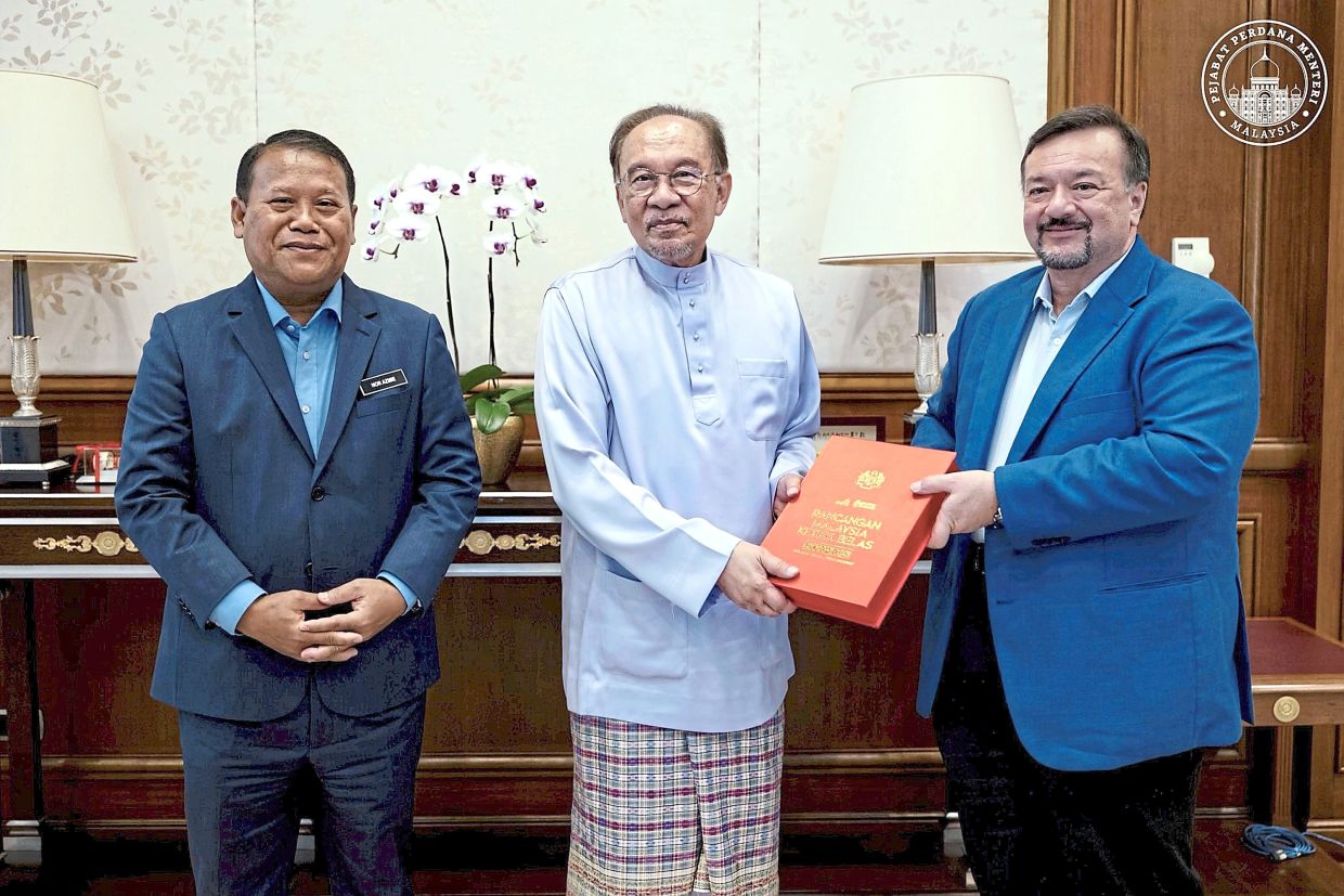Nation’s blueprint: Anwar receiving the 13th Malaysia Plan (13MP) from Finance Minister II Datuk Seri Amir Hamzah in Putrajaya. With them is Economy Ministry secretary-­general Datuk Nor Azmie Diron. Anwar is scheduled to table the 13MP in the Dewan Rakyat today. The plan, which outlines the country’s development direction for 2026 to 2030, is the first under his administration. — Photo courtesy of Anwar’s Facebook page