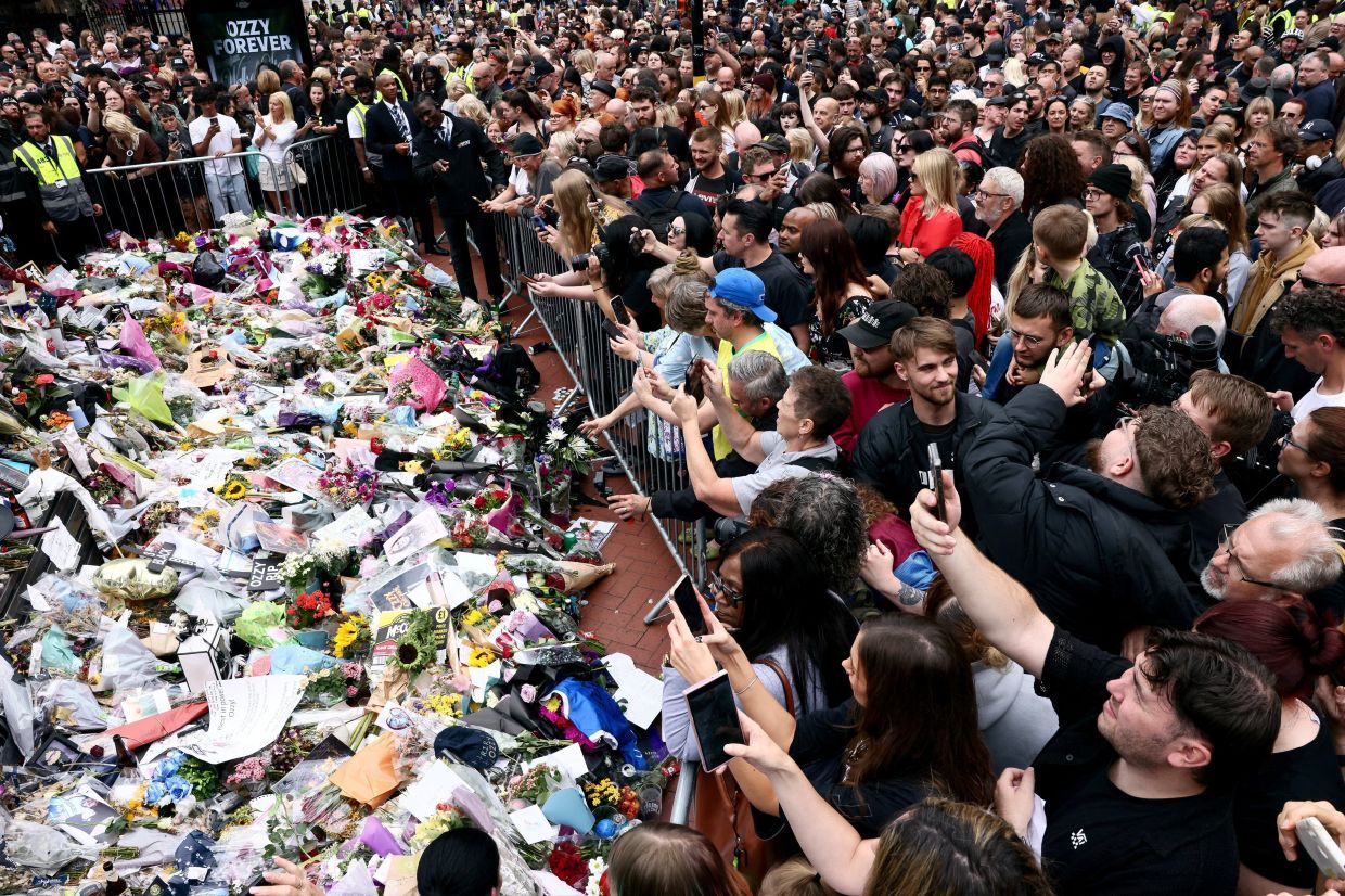 People gather around tributes placed at the Black Sabbath Bridge, named in honour of the heavy metal band, on the day of the funeral cortege of Ozzy Osbourne, its former frontman, in Birmingham, Britain, July 30, 2025. Photo: Reuters