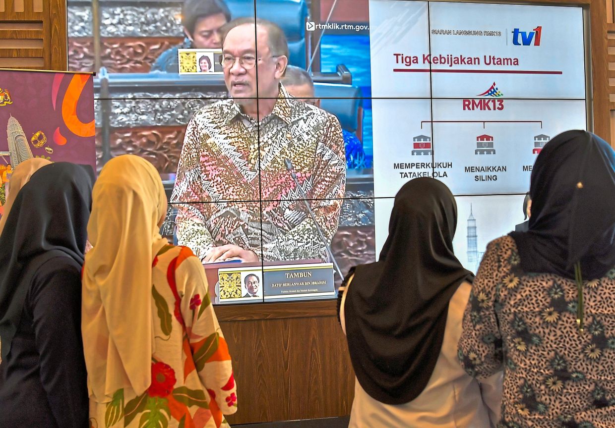 Nouveau cours: fonctionnaire qui regarde en direct une présentation 13MP par Anwar de Putrajaya. - Bernama