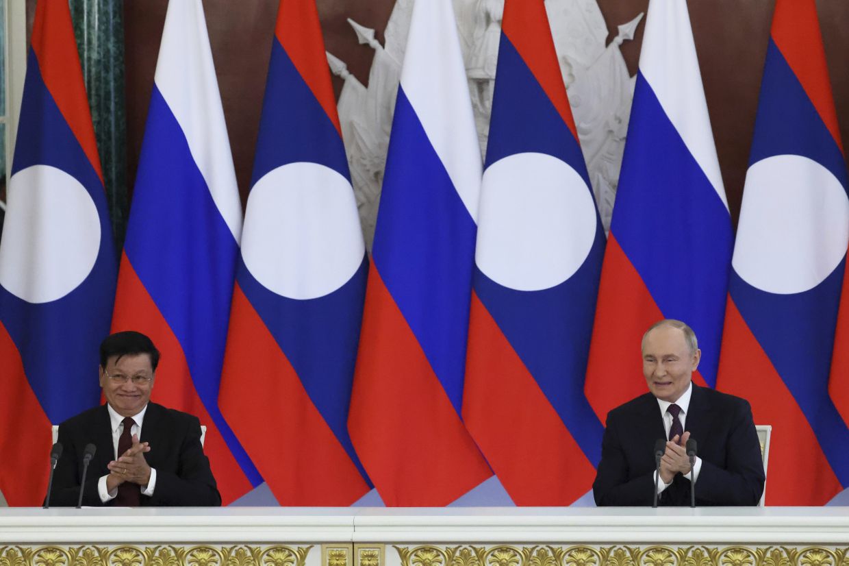 Russian President Vladimir Putin, right, and Laotian President Thongloun Sisoulith applause during a ceremony of exchange of documents following their meeting at the Grand Kremlin Palace in Moscow, Russia. -- AP