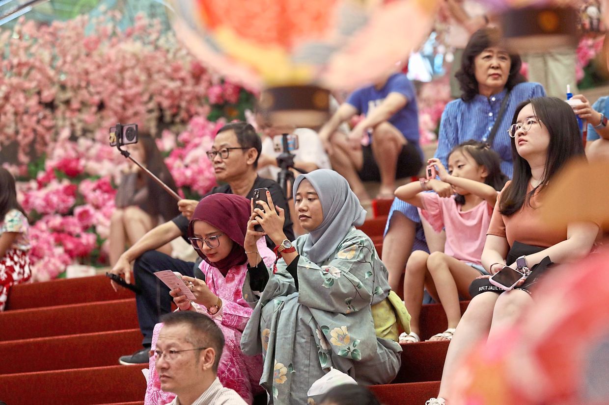 People enjoying the performances at the mall and recording the show.