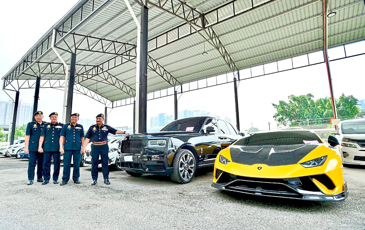 Opulent rides: Muhammad Kifli (right) showing some of the seized luxury vehicles.