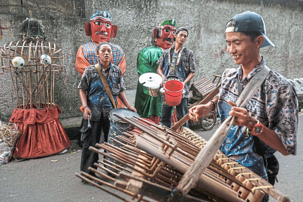 Street performers playing the traditional Indonesian bamboo instruments angklung as they walk past ondel-ondel puppets. Photo: AFP