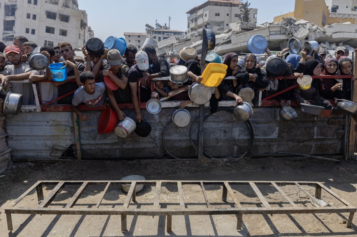 Displaced Palestinians waiting in front of a charity kitchen in the western Gaza City area, July 23, 2025. Famine is unfolding across most of Gaza, a UN-backed food security group said on July 29, citing months of severe aid restrictions imposed by Israel on the territory. — Saher Alghorra/The New York Times