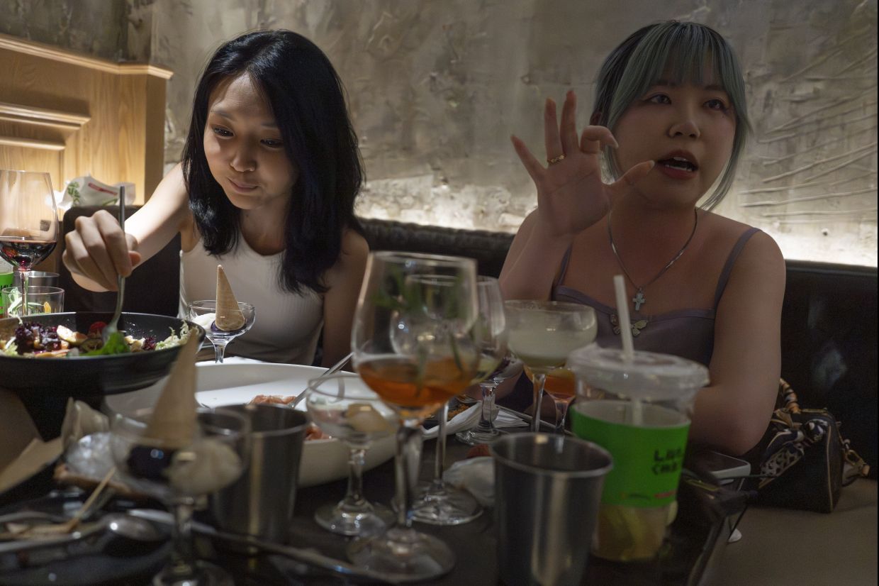 Shirley Huang, out with friends on a Friday night at the bar in Sanlitun, talks about the baijiu spirit at a bar in Beijing, China, Friday, June 13, 2025. (AP Photo/Ng Han Guan)