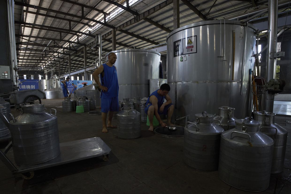 A worker test the baijiu from a vat at Jiangxiaobai Liquor Co.'s Jiangji Distillery in southwestern China's Chongqing on May 19, 2025. (AP Photo/Andy Wong)