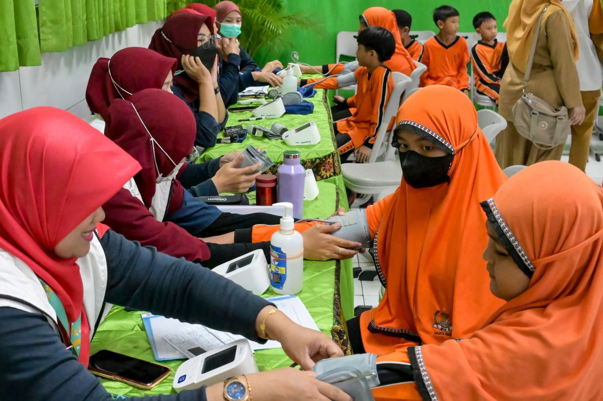 Healthcare workers examine elementary school students during the launch of a free health check programme for children, in Jakarta on Monday, August 4, 2025. -- Photo by BAY ISMOYO / AFP