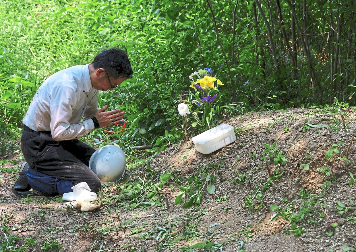 Offering a prayer to the remains he has found. — Reuters