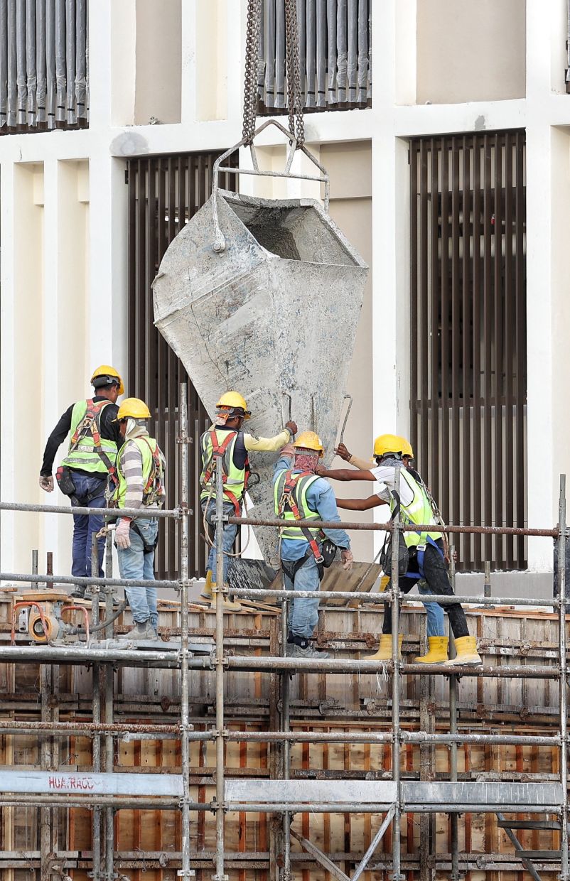 Construction workers are pouring and compacting concrete at a construction project site near Damansara, Kuala Lumpur.— MUHAMAD SHAHRIL ROSLI/The Star