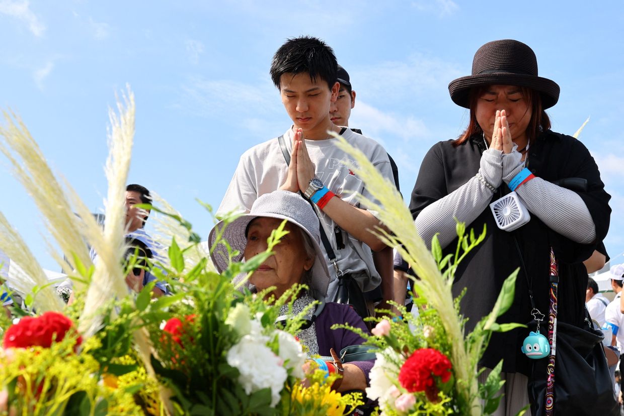 People praying in front of the cenotaph for the victims of the 1945 atomic bombing, at the Peace Memorial Park in Hiroshima on Aug 6, 2025. - Reuters