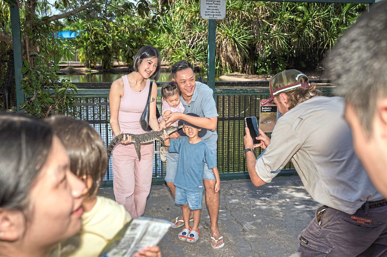 A family poses for a photograph with a juvenile crocodile at Crocodylus Park, a wildlife attraction in Darwin.