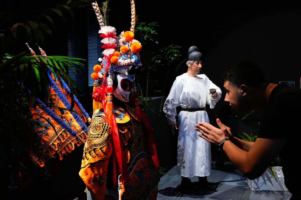 A visitor gestures to an opera robot on display at the Robot Mall, said to be the world's first humanoid intelligent robot 4S store, in Beijing, China, Wednesday, Aug. 6, 2025. — AP